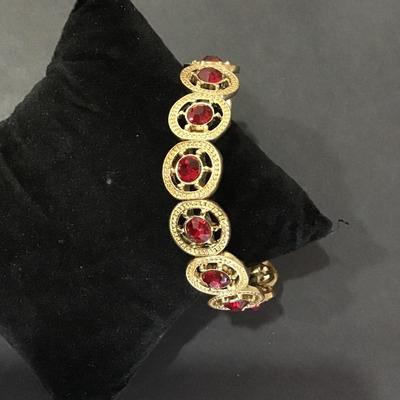 Gold tone, stretch bracelet with red rhinestones