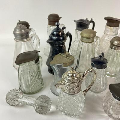 Sale Photo Thumbnail #1307: Total of 17 items
Two green glass pitchers, 15 clear glass pitchers
Only one has no top, one has broken top hinge
Tallest: 7" high
Shortest: 4" high