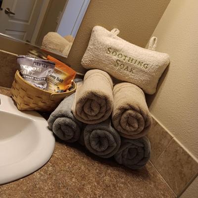 LIGHT TEAL AND TAN BATH TOWELS, EPSON SALT AND A PILLOW FOR SOAKING IN THE TUB