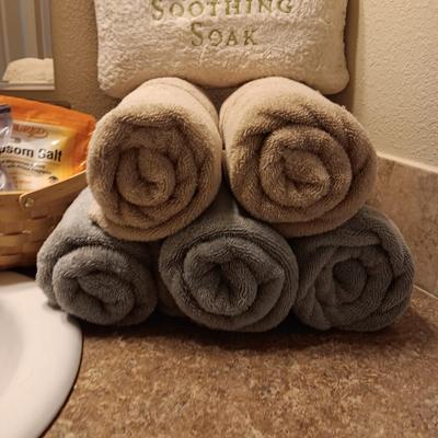 LIGHT TEAL AND TAN BATH TOWELS, EPSON SALT AND A PILLOW FOR SOAKING IN THE TUB