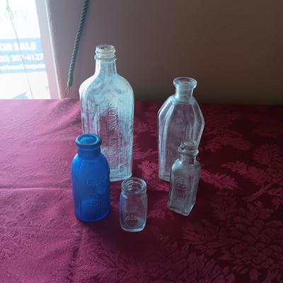 AN ASSORTMENT OF ANTIQUE BOTTLES WITH RAISED LETTERING