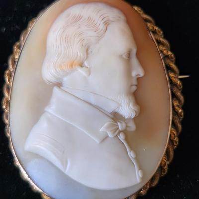Sale Photo Thumbnail #111: The carving depicts a fine gentleman, perhaps on his Grand Tour, by his attire and hairstyle.  The fine detail 
points to a renowned carver, not identified.  The cameo is set in 14K gold frame, with 10k gold or gold plate braiding.  Victorian or Edwardian