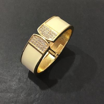 Sale Photo Thumbnail #152: Very nice gold tone with cream enamel and rhinestone hinged bracelet. Please see attached photos.