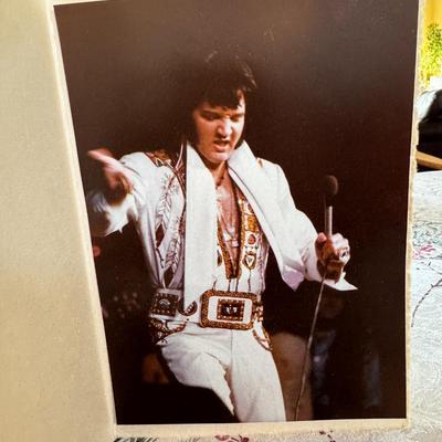 Sale Photo Thumbnail #523: The image shows Elvis Presley performing in concert. Based on the costume he is wearing, particularly the white jumpsuit with the eagle design, it is likely that this image was taken during his 1973 "Aloha From Hawaii" special, or a subsequent performance