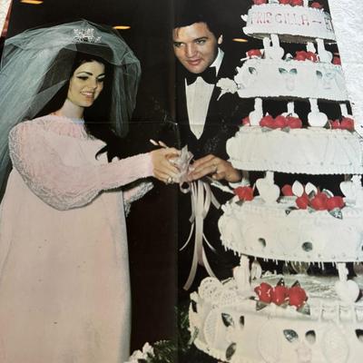 Sale Photo Thumbnail #490: Side one of poster shows Elvis Presley in his United States Army uniform, with the text "Elvis in the Army" visible. 
Side two Elvis and Priscilla Presley cutting their six-tier wedding cake. They were married on May 1, 1967 at the Aladdin Hotel in Las Ve