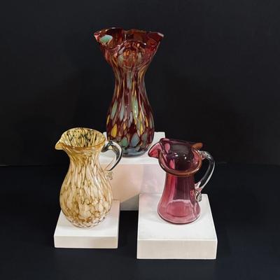 LOT 115: Beautiful Glass Collection: Amber/Gold Handblown Pitcher, Multi Color Art Glass Vase (orange, red, blue) and Cranberry Pitcher