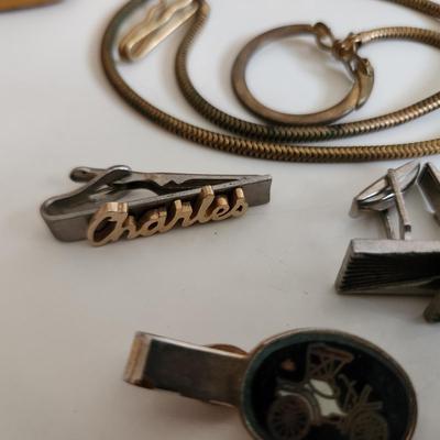 Sale Photo Thumbnail #217: This auction lot is for a Swank Box of Men's Jewelry. This item has all types of men's jewelry.  There is a brass railroad-type watch fog, several tie tack, pins and bars, a nice collection of cuff links - some with trains and other with musical motifs. I
