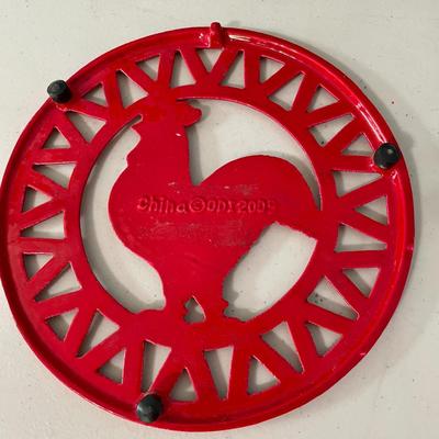Pair of metal roosters and red metal trivet