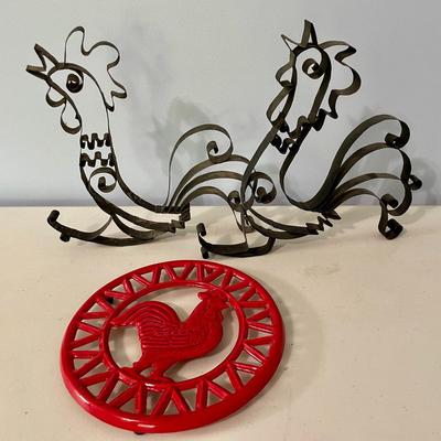Pair of metal roosters and red metal trivet