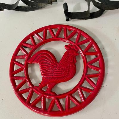 Pair of metal roosters and red metal trivet