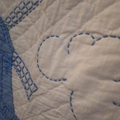 Sale Photo Thumbnail #626: looks to be hand embroidered.  Dutch girl and windwmill it is approx 4 ft wide (did not actually measure it but he rack it's hanging from is a 4ft rack that is 6ft tall, the quilt is not touching the floor but it does span end to end on the rack.