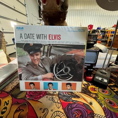Sale Photo Thumbnail #48: "A Date with Elvis" by Elvis Presley.
Here's more information about this record:
Artist: Elvis Presley
Title: A Date with Elvis
Format: The image displays a vinyl LP record album, identifiable by its square shape and the depiction of the record label (RCA