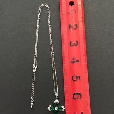 Silver toned necklace with silver tone cross with green rhinestones