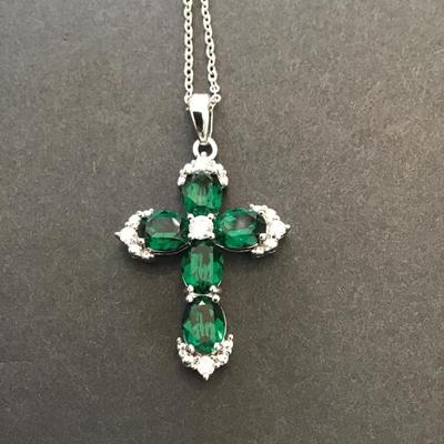 Silver toned necklace with silver tone cross with green rhinestones
