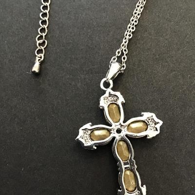 Silver toned necklace with silver tone cross with green rhinestones