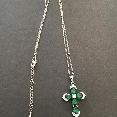 Silver toned necklace with silver tone cross with green rhinestones