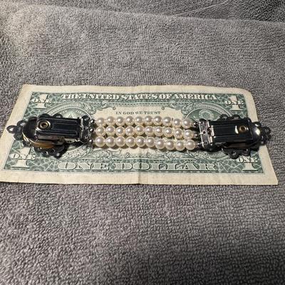 Triple-strand pearl sweater clip featuring a distinctive, ornate silver-toned clasp,