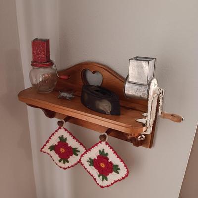 WOODEN WALL SHELF, 2 HAND CRANKED GRINDERS, CAST CLOTHES IRON, PEWTER PIG AND 2 HANDMADE POT HOLDERS