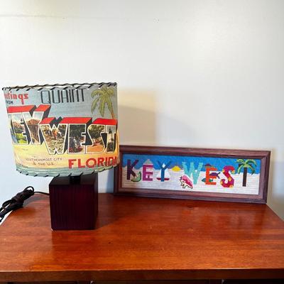 Sale Photo Thumbnail #64: Needle point is framed and measures 18.25" x 6.25" with table lamp with lamp shade that does not sit on straight measuring 14"H