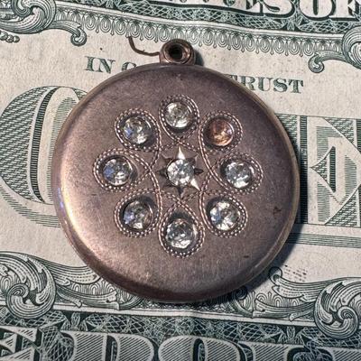 4 leaf clover locket pendant, with clear stones in a decorative, floral or starburst pattern.