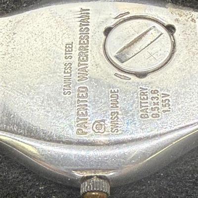 Sale Photo Thumbnail #298: Larger numbers 12, 7, and 7 are printed backwards on the dial.  Silver tone case with brown leather band. Not running, most likely needs a new battery.
