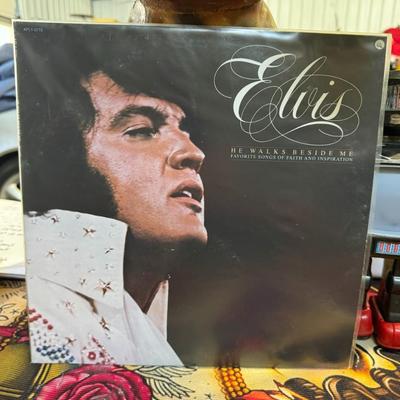 Sale Photo Thumbnail #180: "He Walks Beside Me, Favorite Songs Of Faith And Inspiration" by Elvis Presley. 
Additional details about the album include:
Artist: Elvis Presley.
Title: He Walks Beside Me, Favorite Songs Of Faith And Inspiration.
Genre: Gospel music.
Label and Catalog 