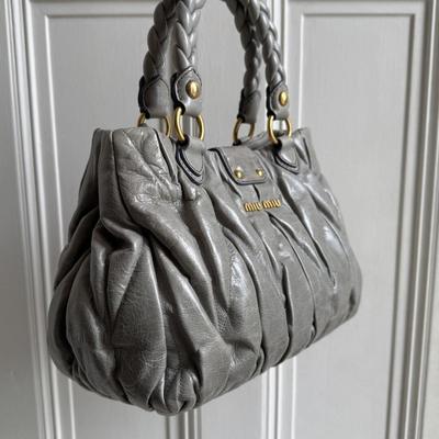 Sale Photo Thumbnail #14: Expertly crafted from grey leather with gold hardware, the Miu Miu Matelasse Grey Leather Handbag is the ultimate in luxury and style. The elegant design features a magnetic compartment and zip-up pocket, perfect for storing all your essentials. With a go