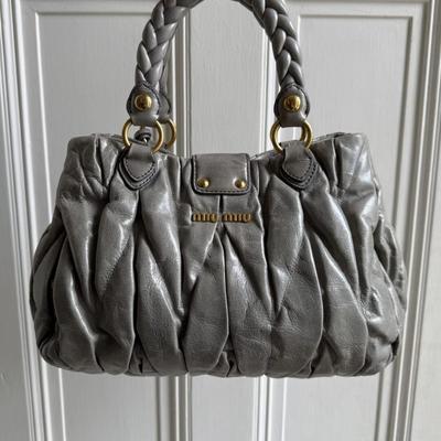 Sale Photo Thumbnail #15: Expertly crafted from grey leather with gold hardware, the Miu Miu Matelasse Grey Leather Handbag is the ultimate in luxury and style. The elegant design features a magnetic compartment and zip-up pocket, perfect for storing all your essentials. With a go