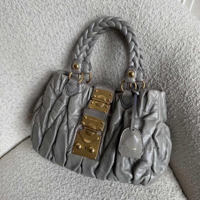 Sale Photo Thumbnail #16: Expertly crafted from grey leather with gold hardware, the Miu Miu Matelasse Grey Leather Handbag is the ultimate in luxury and style. The elegant design features a magnetic compartment and zip-up pocket, perfect for storing all your essentials. With a go