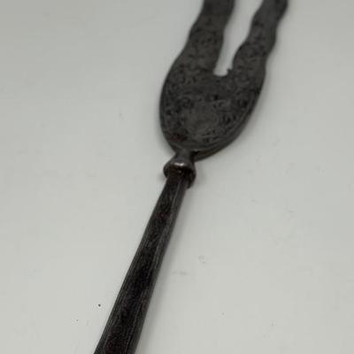 Sale Photo Thumbnail #24: 13” blade 9” shaft
Persian wavy two-pronged spearheads have been in use since the 16th Century. The majority of examples available today date back to the Qajar period. The base of the blade is decorated with chiseled ornate motifs along with small inl