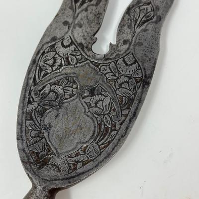 Sale Photo Thumbnail #26: 13” blade 9” shaft
Persian wavy two-pronged spearheads have been in use since the 16th Century. The majority of examples available today date back to the Qajar period. The base of the blade is decorated with chiseled ornate motifs along with small inl