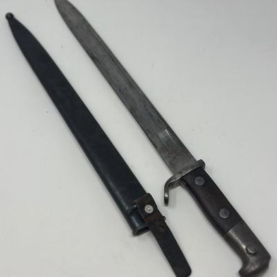 Sale Photo Thumbnail #80: Blade is 11 3/4” long and 17 1/2” long overall 
Waffenfabrik Neuhausen Bayonet. Stamped 460779. Inlaid metal swastika in wooden and metal hilt.