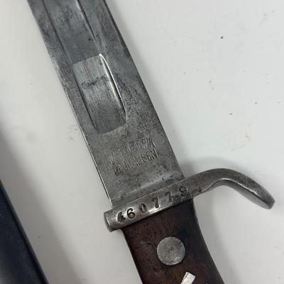 Sale Photo Thumbnail #77: Blade is 11 3/4” long and 17 1/2” long overall 
Waffenfabrik Neuhausen Bayonet. Stamped 460779. Inlaid metal swastika in wooden and metal hilt.