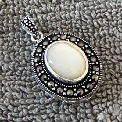 Sterling silver pendant featuring a mother of pearl cabochon surrounded by marcasite accents
