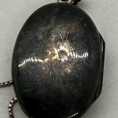 Sale Photo Thumbnail #163: 24" necklace chain. Cameo pendant opens to reveal 2 spaces for small oval photos. Oval stone looks to be made of onyx.
