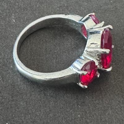 Three-stone ring featuring vibrant red rhinestones/cubic zirconia, set in what appears to be a silver-toned metal,