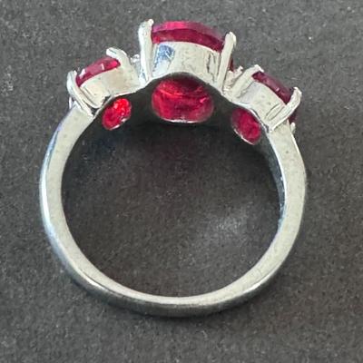 Three-stone ring featuring vibrant red rhinestones/cubic zirconia, set in what appears to be a silver-toned metal,