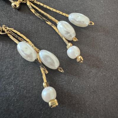 Vintage-style gold-tone dangle earrings with white beaded accents,