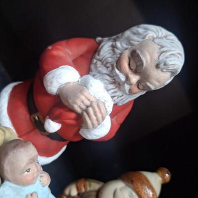 Santa praying over Baby Jesus and other santas