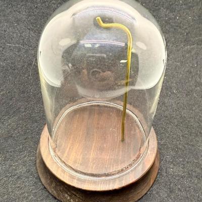Sale Photo Thumbnail #569: Round wooden base with a brass post with hook, to display a pocket watch, handing ornament, or mother item,  Clear glass dome cover, which is removable. Good condition, approx. 5" tall overall.