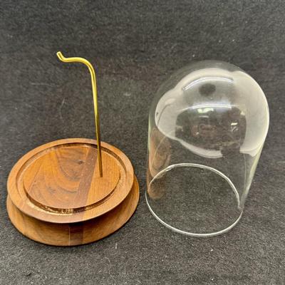 Sale Photo Thumbnail #571: Round wooden base with a brass post with hook, to display a pocket watch, handing ornament, or mother item,  Clear glass dome cover, which is removable. Good condition, approx. 5" tall overall.