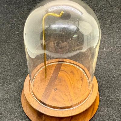 Sale Photo Thumbnail #568: Round wooden base with a brass post with hook, to display a pocket watch, handing ornament, or mother item,  Clear glass dome cover, which is removable. Good condition, approx. 5" tall overall.