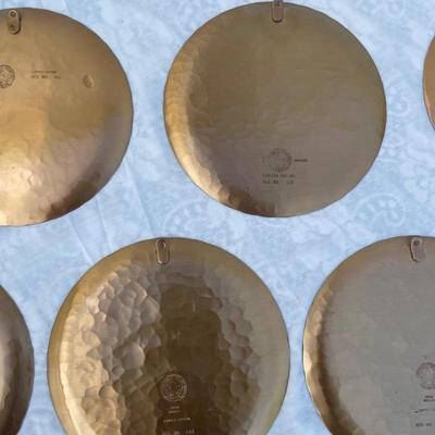 Sale Photo Thumbnail #139: 9 vintage Wendell August Forge Limited Edition Christmas Plates, years 1981-1988. Duplicates of 1985 and 1986, missing 1987. Various Christmas designs on solid brass plates with dimpled texture. In good condition and each plate has a small hook on the bac