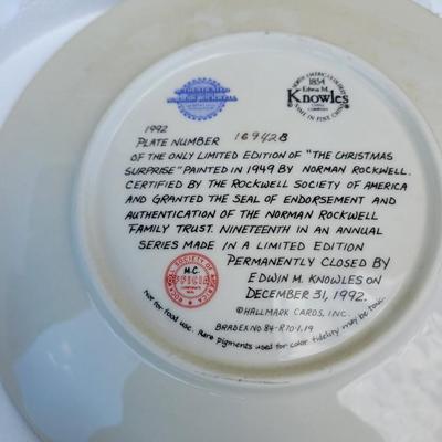Sale Photo Thumbnail #334: 1992 Norman Rockwell collector's plate titled "The Christmas Surprise". 
It is the 19th plate in an annual series of limited edition Christmas plates by Norman Rockwell. 
The plate is hand-numbered and was issued by the Rockwell Society of America and Kno