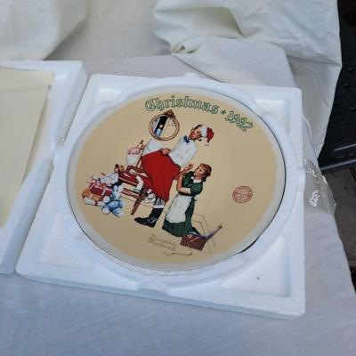 Sale Photo Thumbnail #333: 1992 Norman Rockwell collector's plate titled "The Christmas Surprise". 
It is the 19th plate in an annual series of limited edition Christmas plates by Norman Rockwell. 
The plate is hand-numbered and was issued by the Rockwell Society of America and Kno