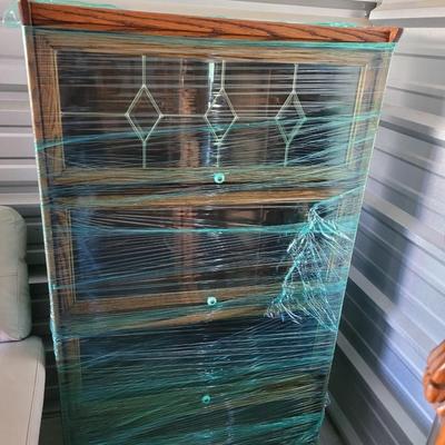 Sale Photo Thumbnail #606: I've left this one wrapped and will wrap it more for transport and for the buyer to view. It's in perfect condition, doors open upwards and slide in, top is leaded glass, measures 60" tall, 33" wide and 12" deep. There is am earlier matching one up for au