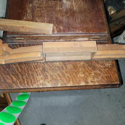 Sale Photo Thumbnail #793: Antique Singer Sewing Machine Table Plus Sewing Accoutrements (Lot of 4). Sewing machine with original table and foot pedal, cast iron and wood details. Also includes folding wooden box of different sewing feet, Singer buttonhole making foot, and pin cush