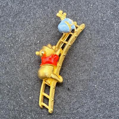 Sale Photo Thumbnail #459: This is a brooch/pin has Pooh climbing a ladder to reach a pot of honey. .It measures 1 inches  high x 2.5 inches wide. Very good condition.