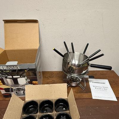 Sale Photo Thumbnail #180: 16 piece 18/8 stainless steel fondue pot set. Includes 6 forks, 6 black ceramic ramekins, splatter shield, adjustable universal burner with snuffer, stand and wood handle. In excellent condition.