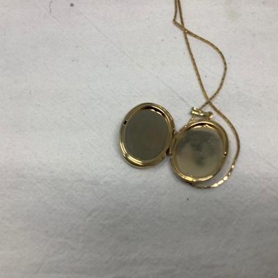 Sale Photo Thumbnail #255: Two gold necklaces one has black locket with gold inside.  The other is gold necklace with 5 charms.